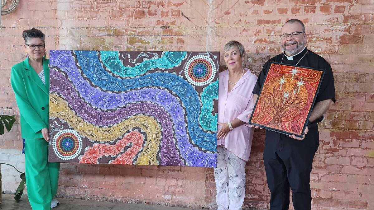 2023 CatholicCare Wilcannia-Forbes Aboriginal Art Competition judges Bishop Columba Macbeth-Green of the Catholic Diocese of Wilcannia-Forbes (right), CatholicCare Wilcannia-Forbes CEO Anne-Marie Mioche (centre) and Red Bend Catholic College visual arts teacher Tracie Axton (left) with the two paintings awarded first prize. Picture supplied